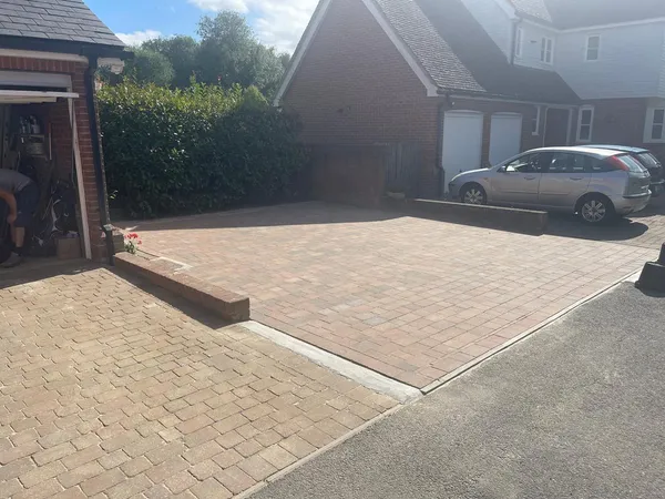 Buff and brindle herringbone block paving driveway with a soldier-course border at a red-brick detached house