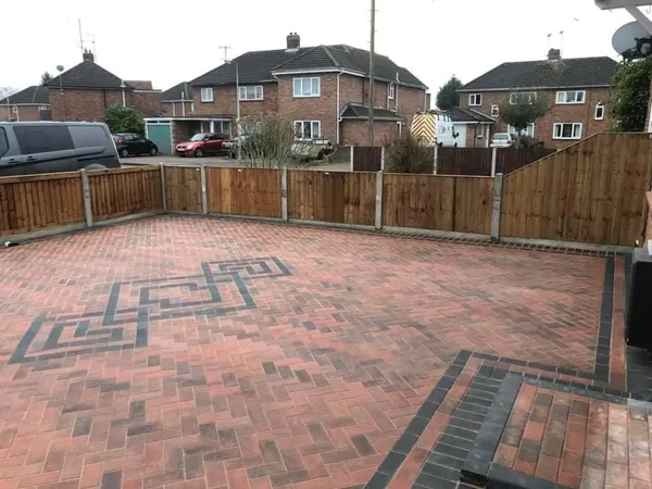 Red herringbone block paving driveway with an interlocking pattern inlaid in charcoal pavers