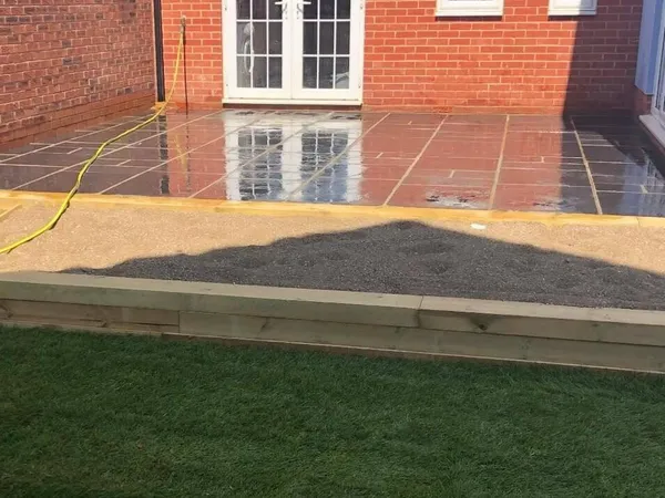 Black limestone patio by French doors with a sleeper-edged raised bed and new turf
