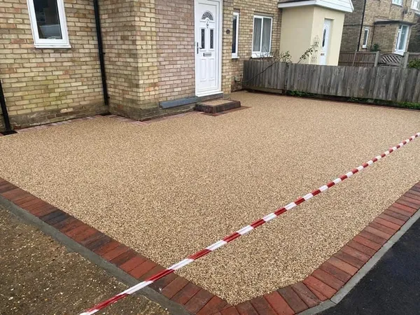Golden resin bound driveway with a red brick border at a brick semi