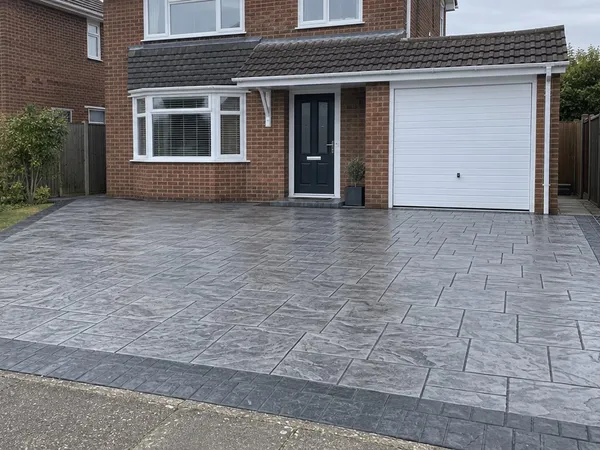 Sealed grey slate-pattern imprinted concrete driveway with a charcoal border