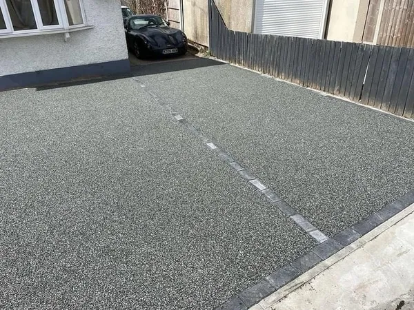 Silver-grey resin bound driveway with charcoal block edging at a white bungalow